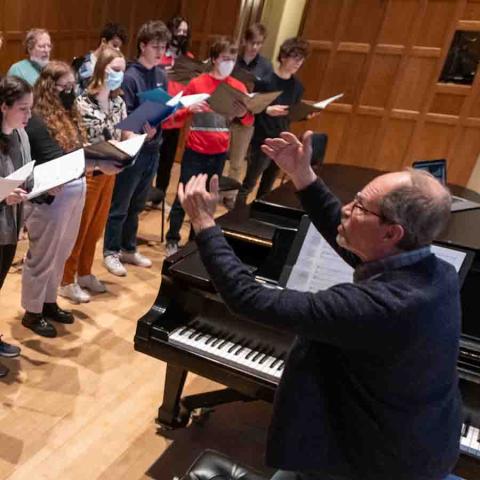 Man at piano conducting a choir