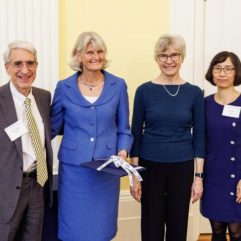 Four people standing side-by-side in a brightly lit room smiling for the camera.
