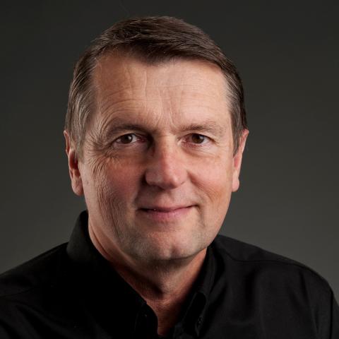 Headshot of Ed Larson, a person with short dark hair and a black shirt.