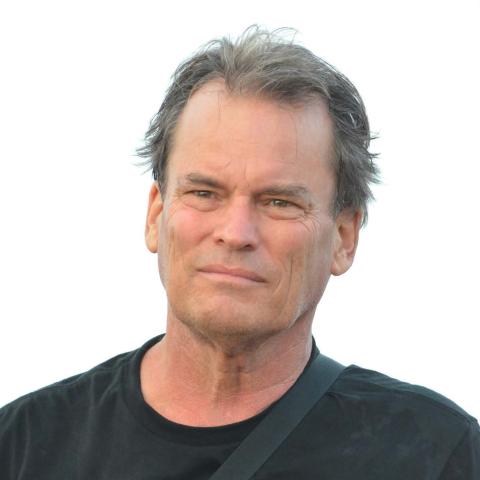Person with salt-and-pepper short hair facing the camera, wearing a dark colored t-shirt.