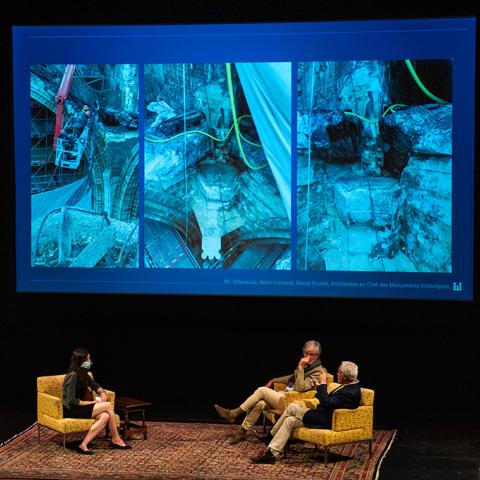 Three people sitting with a projected image in the background.