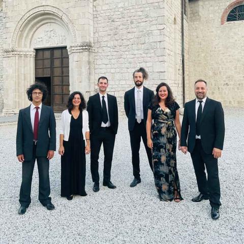 Group of people in formal attire standing in front of a building.