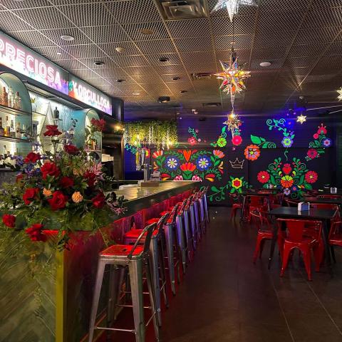 Restaurant and bar with bright red, blue and green colors, red chairs and black tables.