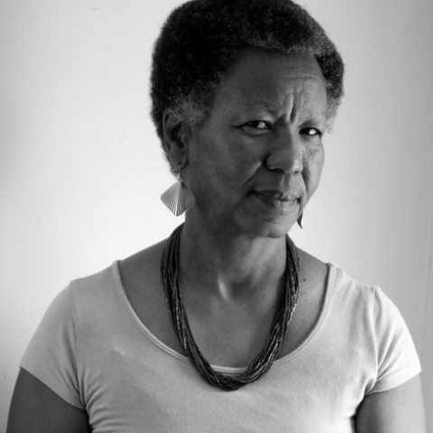 Portrait with white shirt, thick-beaded necklace, in a black and white image.