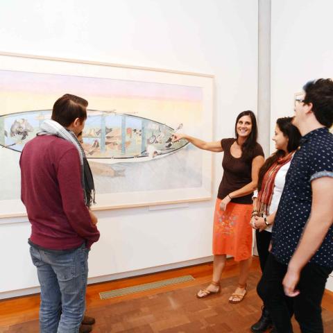 People in an art gallery discussing a work on the wall.