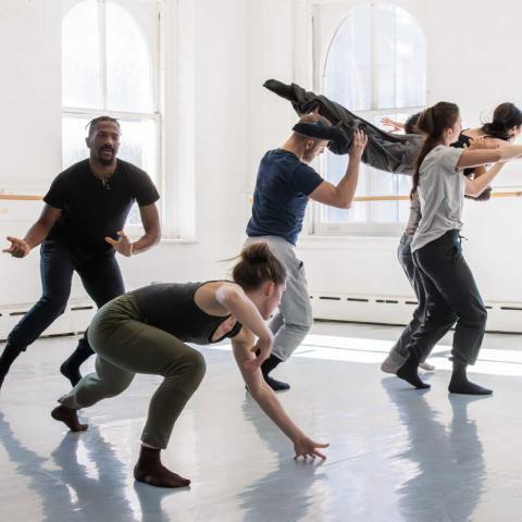 Six people practice dancing in a spacious, well-lit room.