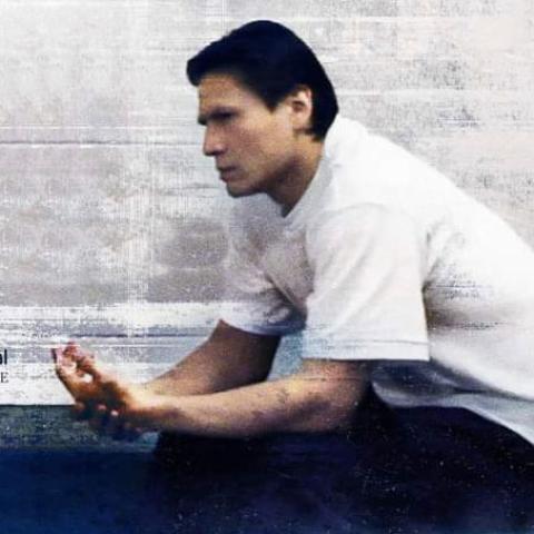 Side view of a person sitting in front of a cinder block wall with a very serious expression.