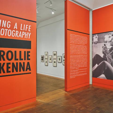 A photo of a large, spacious art gallery with a display on the walls that reads "Making a Life in Photography: Rollie McKenna" in large letters.