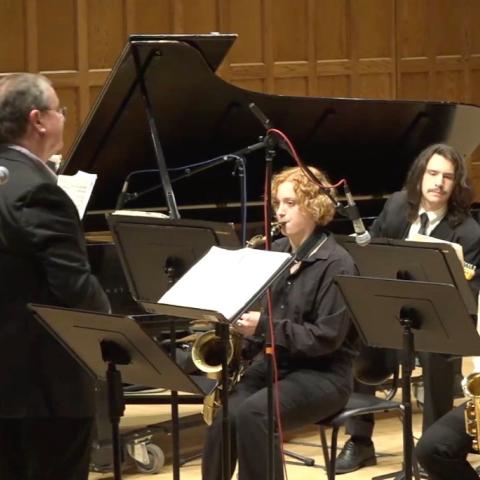 Performance with the conductor in the foreground and musicians in the background