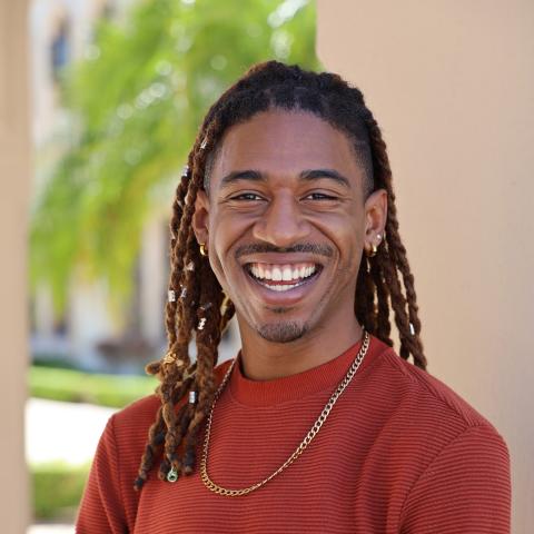 Pictured: Matt Ford. Picture of a man with dreadlocks, a slamond colored shirt, and thick gold necklace smiling.