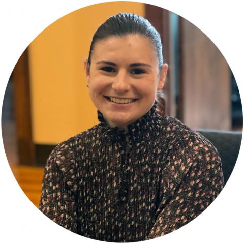 Portrait of a person smiling in a spotted brown turtle neck sweater.