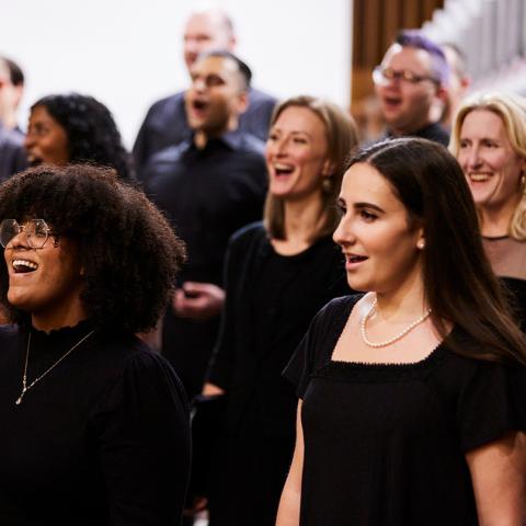Close-up of a choir, eight members singing in a concert, all wearing black