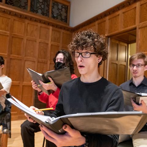Rehearsal image focused on one singer with others in the background.