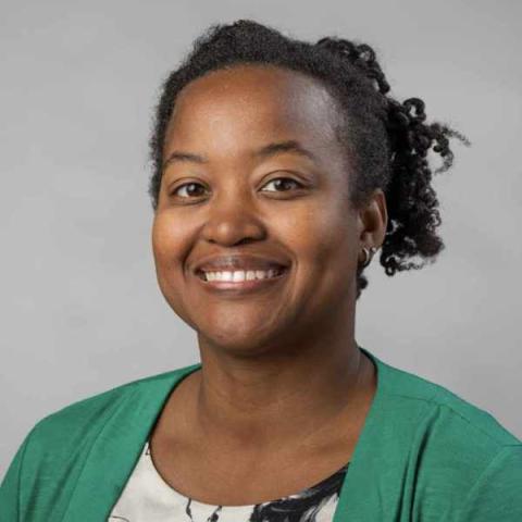 A portrait of Kelli Duncan, a person with short black hair and a green shirt.
