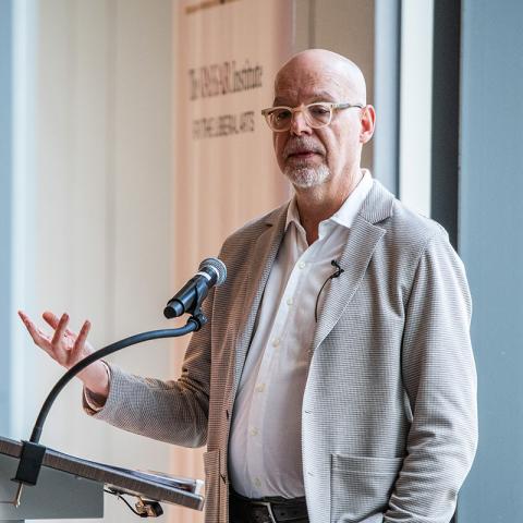 Person standing in front of an audience speaking.