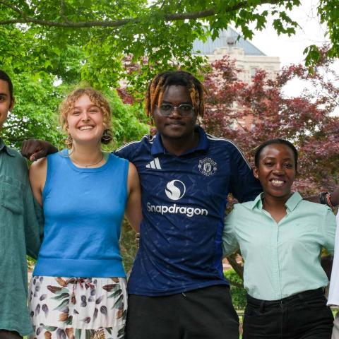 A group standing together smiling, with trees in the background.