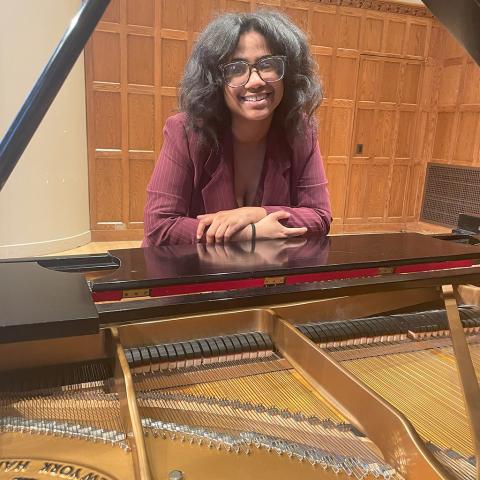 Person standing with open piano in the foreground.