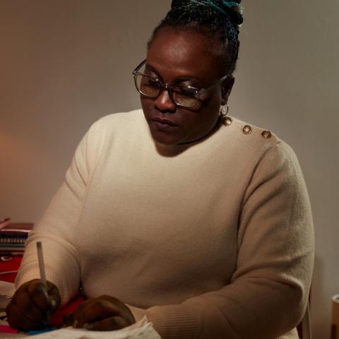 Photo of Patricia Achiro Olwoch looking down and writing in a notebook.