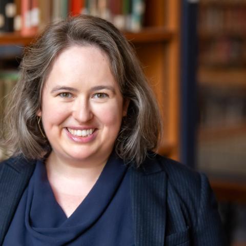 Portrait of a person with library book shelves in the background.