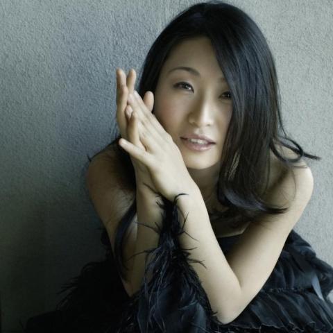 portrait-style image of subject holding hands together near face.