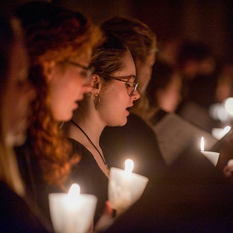 Detail of performance focussed on singers with candlight in the background.