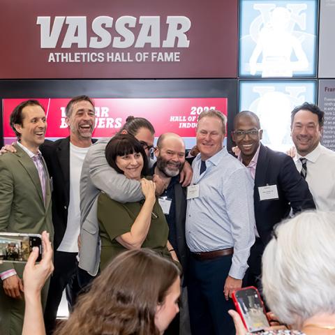 A celebratory group picture with a wall honoring the Hall of Fame inductees in the background.