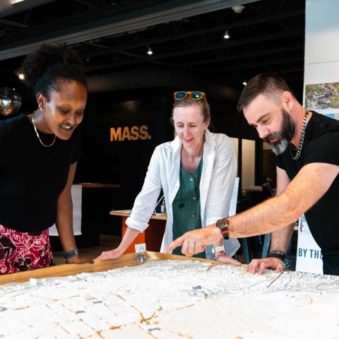 Three people looking over a map while one of the people points something out.