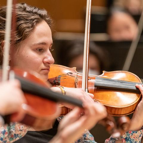 Detail of performance focused on a violinist actively playing.