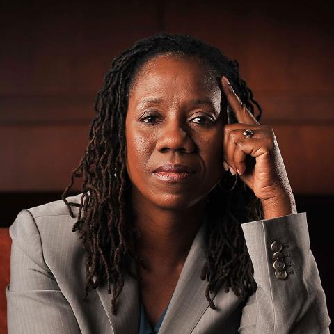 Pictured: Sherrilyn Ifill '84. Person in a gray pinstripe suit with their head on one hand, looking directly at the camera with a thoughtful expression.