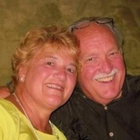 Husband and wife smiling together closely for the camera.