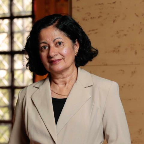 A portrait photo of Jyotsna Vaid posing in front of backlit ornate windows.