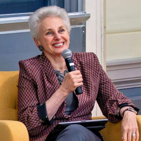 Seated person smiling and holding a microphone.