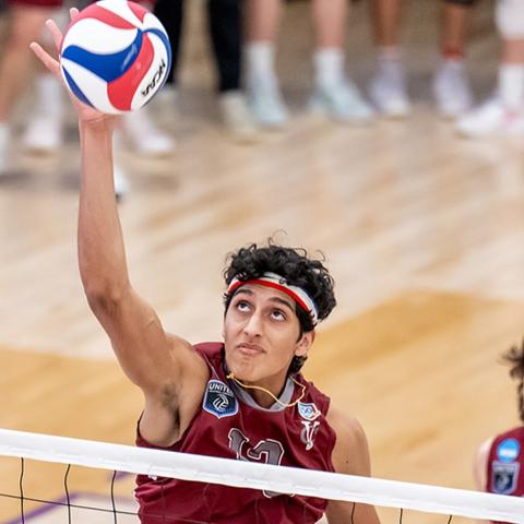 Volleyball player reaching up for a ball in the air.