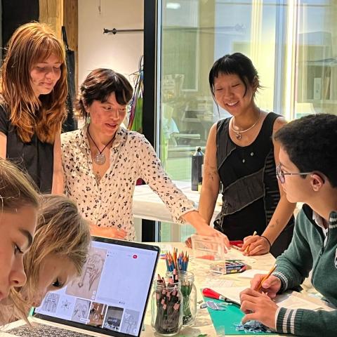 A group of college students are in a room working with high school students.