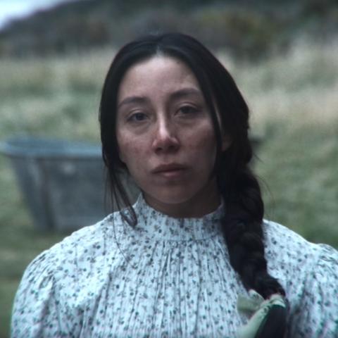 Photo portrait of a person standing in front of a grassy hill.