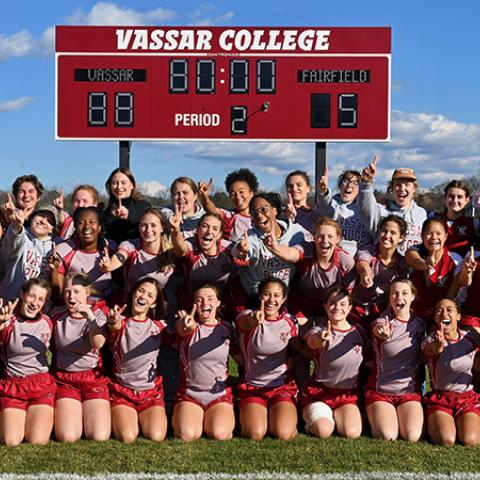 Elated team poses for group photo with the scoreboard in the background (Vassar 88, Fairfiled 5).