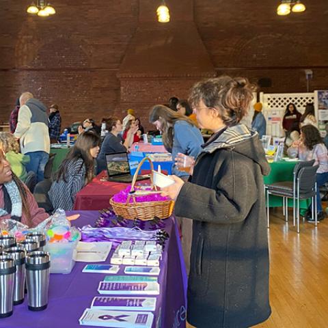 Candid photo of a community fair, with tables for different organizations with attendees in conversation with people at their tables.