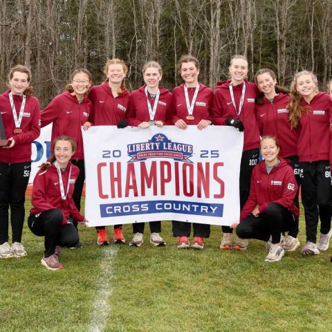 Team photo with athletes holding a banner that reads: 2025 Liberty League Champions Cross Country.