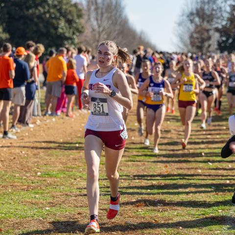 A runner races ahead of the pack on an outdoor course.