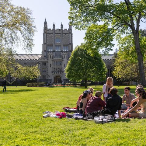 Group of students sitting in a circle on a campus lawn