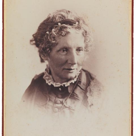 An 1800's sepia-toned photo of a woman wearing a headband and filly collar.