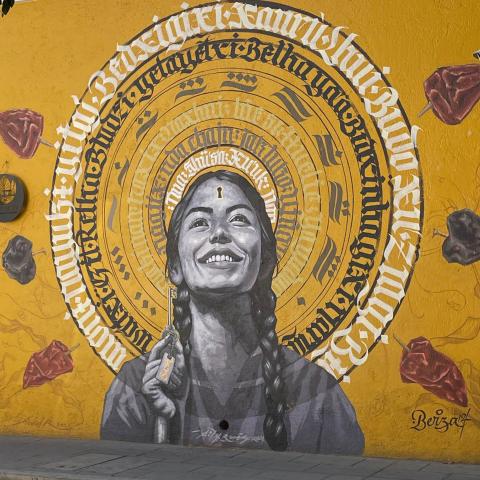 A young woman with a halo adorns a mural with a gold-colored background.