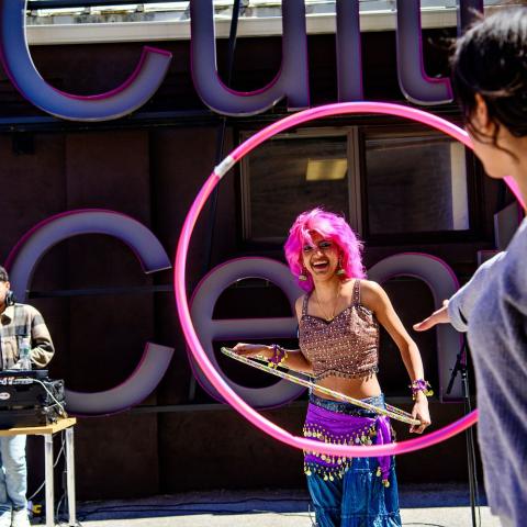 Outdoor party with a DJ behind the decks and a person using a hoola hoop.