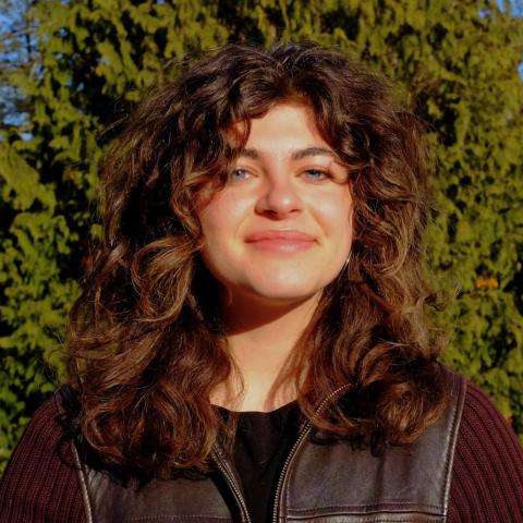 Avery Epstein smiles warmly in an outdoor portrait, with trees in the background.