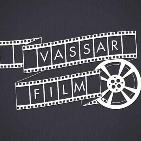 A dark gray background features white film strip elements curling around the words "Vassar" and "Film." The film strips have alternating solid and perforated sections, creating a dynamic visual flow. To the right, a stylized film reel adds detail, showcasing circular motifs with inner spokes. The overall composition emphasizes a classic cinematic theme, with balanced lettering and shapes that evoke the film industry.