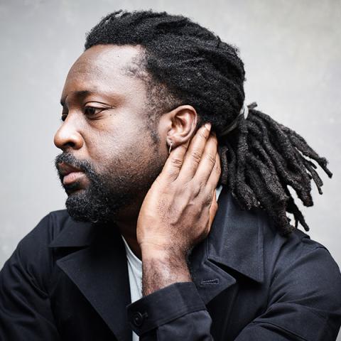 Portrait of subject in profile, looking to the distance with left hand resting on neck and head.