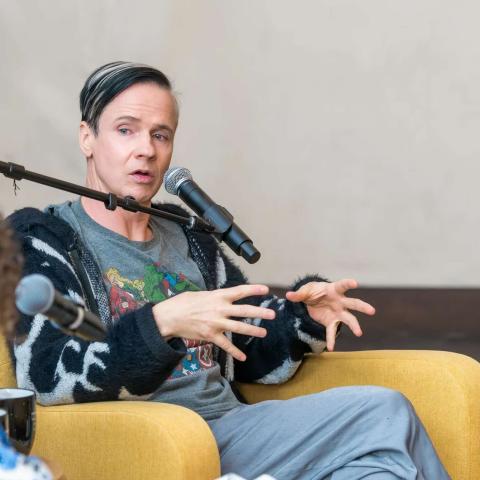 Person in a chair addressing an audience.