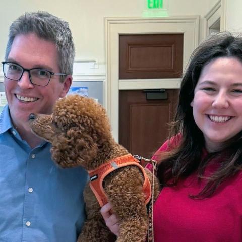 Two smiling people holding a dog.