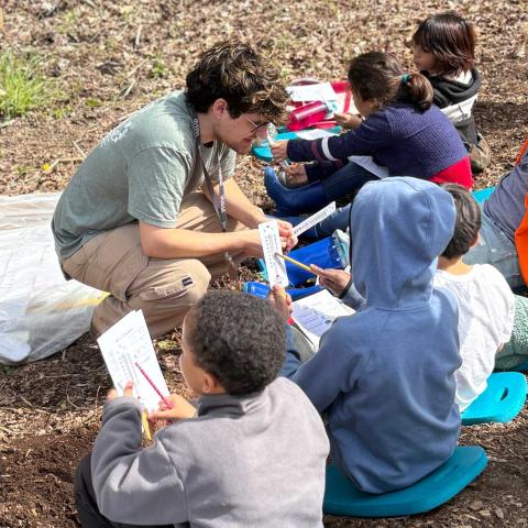School age children with teacher in the field looking at thermometers.