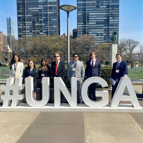 Students standing in front of a sign that reads #UNGA.